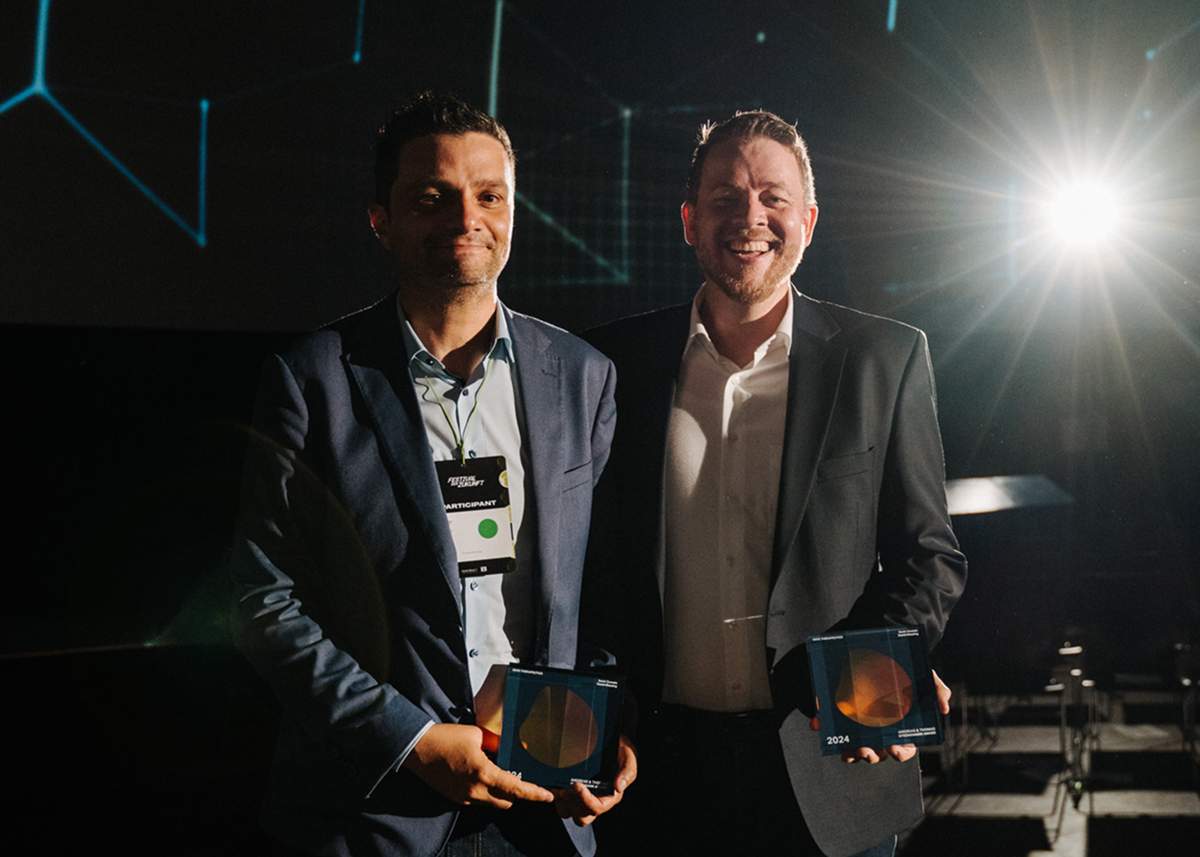 Two team members holding awards on stage during a recognition event, representing company excellence and achievement.
