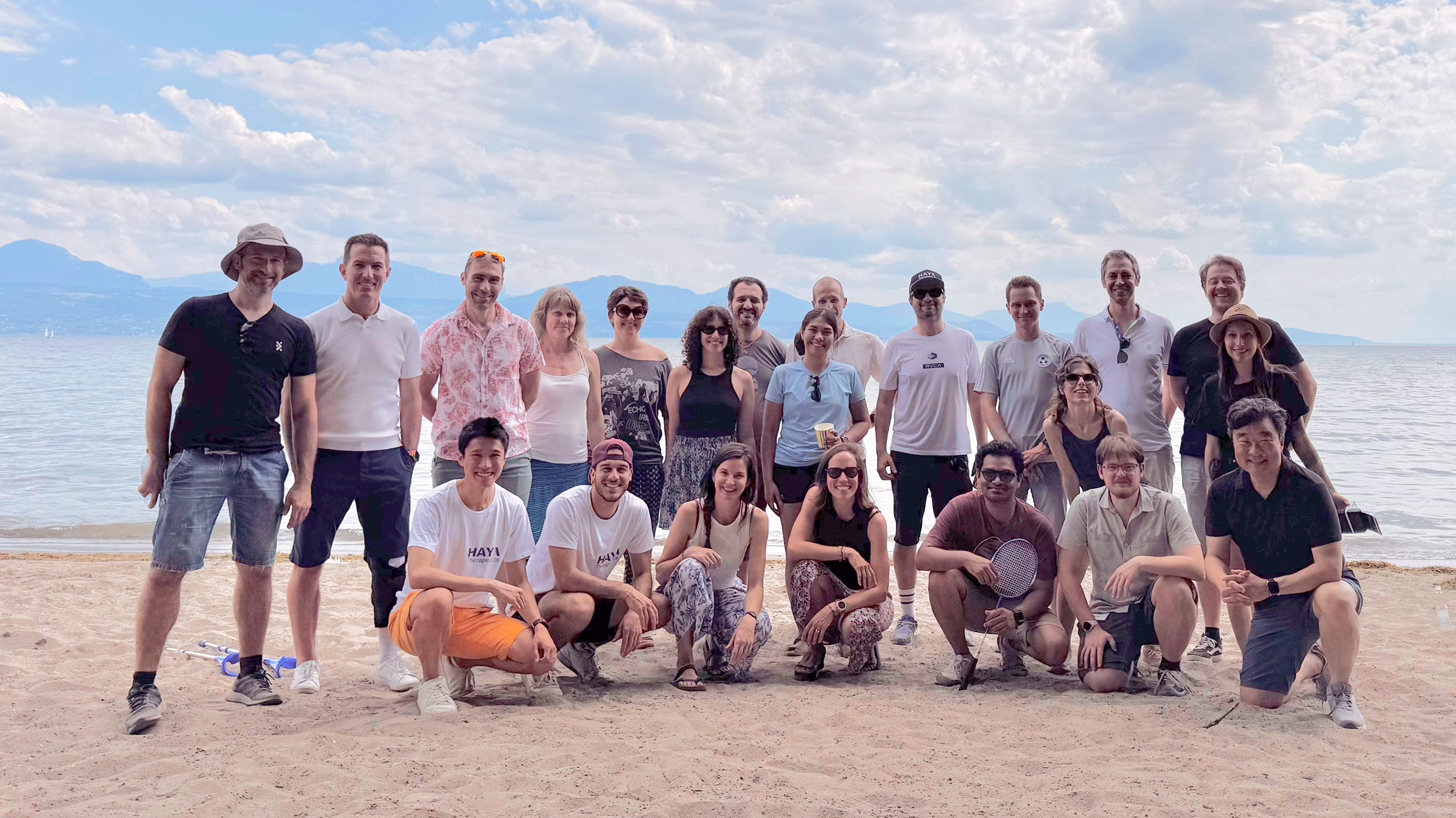 Team members gathered on the beach during a company event, representing a collaborative and positive workplace culture.